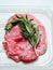 Juicy uncooked lamb leg steak with green fresh rosemary on plastic tray. Uncooked high quality meat product with rich taste and