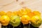 Juicy yellow and green tangerines and leaves of ginkgo tree on a fresh raw wooden table.