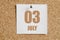 july 03. 03th day of the month, calendar date.White calendar sheet attached to brown cork board.Summer month, day of the