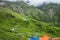 July 14th 2022, Himachal Pradesh India. Multiple colorful tents at Bheem Dwari base camp with beautiful mountains peaks and
