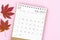 The July 2023 desk calendar for 2023 year with autumn maple leaf on pink color background