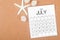 The July 2023 Monthly calendar with Starfish on wooden background