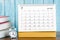 The July 2023 Monthly desk calendar for the organizer to plan 2023 year with alarm clock and books on wooden table