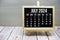 July 2024 monthly calendar on easel stand on wooden background