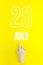 July 20th. Day 20 of month, Calendar date.Hand finger pointing at a calendar date on yellow background.Summer month, day of the