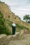 July 29, 2023. Russia, Republic of Dagestan, Derbent, a Muslim woman in a green dress and a white khimar near the wall