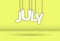 JULY. The word consists of letters hanging on a rope