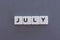 July word made of square letter word on grey background