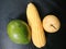 Jumbo sized corn and pear fruit and avocado on black leather board