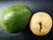 Jumbo sized ripe avocado adn pear on black leather board