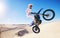 Jump, sports and man on motorcycle on sand for adrenaline, adventure and freedom in desert. Action, extreme motorbike