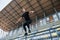 Jumping and doing parkour on the bleachers. Sportive young guy in black shirt and pants outdoors at daytime