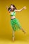 Jumping funny girl in summer bright clothes having positive emotion posing at yellow studio