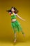 Jumping funny girl in summer bright clothes having positive emotion posing at yellow studio