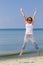 Jumping happy woman on the beach, fit sporty healthy body in blue jeans, woman enjoys wind, freedom, vacation