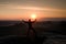 Jumping hiker in black celebrate triumph between two rocky peaks. Wonderful daybreak with sun above head..