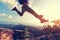 Jumping over precipice between two rocky mountains at sunset