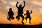 Jumping silhouette of happy boys and girls at sunset