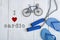 Jumping/skipping rope with blue handles, flip flops, model of bicycle on white wooden background with text I love cardio
