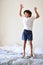 Jumping up for joy. Full length shot of an adorable little boy playing and jumping on a bed at home.