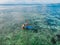 June 06, 2020. Bali, Indonesia. Aerial view of family with child and surfboard in sea. Surfers family relax in water