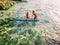 June 06, 2020. Bali, Indonesia. Aerial view of family with child and surfboard in sea. Surfers family relax in water