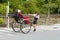 June 2012 - Arashiyama, Japan: An asian man pulling a Pulled rickshaw with two people seating and moving away from the camera