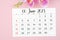 The June 2023 calendar page and pink orchid on pink background