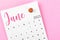 A June 2023 calendar and wooden push pin on pink colour background