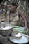Jungle of CAR. Africa. Jungle of the Central-African Republic. Baka woman cooks food, crushing a flour in a mortar