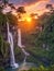 jungle with waterfall and sunset rays in the background.