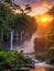 jungle with waterfall and sunset rays in the background.