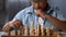 Junior pupil taking part in chess competition thinking over strategy, hobby