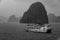 Junk Boat sails into the rain in Ha Long Bay, Vietnam, with rain in the foreground and mist in the distance