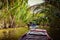 Junk boat tour on a river in the Mekong Delta with palm trees surrounding the water