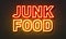 Junk food neon sign on brick wall background.