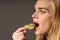 Junk food and unhealthy eating concept. Portrait of young woman who holding fried potato chips at the mouth