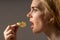 Junk food and unhealthy eating concept. Portrait of young woman who holding fried potato chips at the mouth