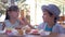 Junk meal for children, caring cute boy feeding girlfriend with french fries during lunch in street fast food cafe