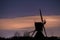 Jupiter and Saturn planets in the night sky appearing over an old Dutch windmill known as Broekmolen