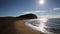 Jurassic coast Dorset at West Bay uk in morning with sun shining on shimmering sea and distant people swimming