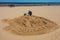 Jurmala, Latvia - May 7, 2017: Man is sculpturing the figure from sand and people are walking on sandy beach on the