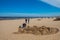 Jurmala, Latvia - May 7, 2017: Man is sculpturing the figure from sand and people are walking on sandy beach on t