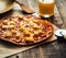 Just baked hawaiian pizza with freshly chopped pineapple and ham on the rustic wooden background. Selective focus