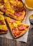 Just baked hawaiian pizza with freshly chopped pineapple and ham on the rustic wooden background. Selective focus