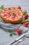 Just baked homemade strawberry cheesecake on the gray background decorated with fresh strawberries, mint leaf, gray cloth