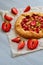 Just baked strawberry tart on the gray concrete background. Vegetarian healthy rhubarb galette decorated with sliced strawberry