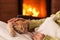 Just chilling by the fireplace - woman hands petting a small tabby cat