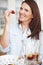 She just couldnt resist...An attractive woman about to eat a strawberry while preparing a smoothie.