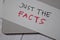 Just The Facts write on sticky note isolated on wooden table